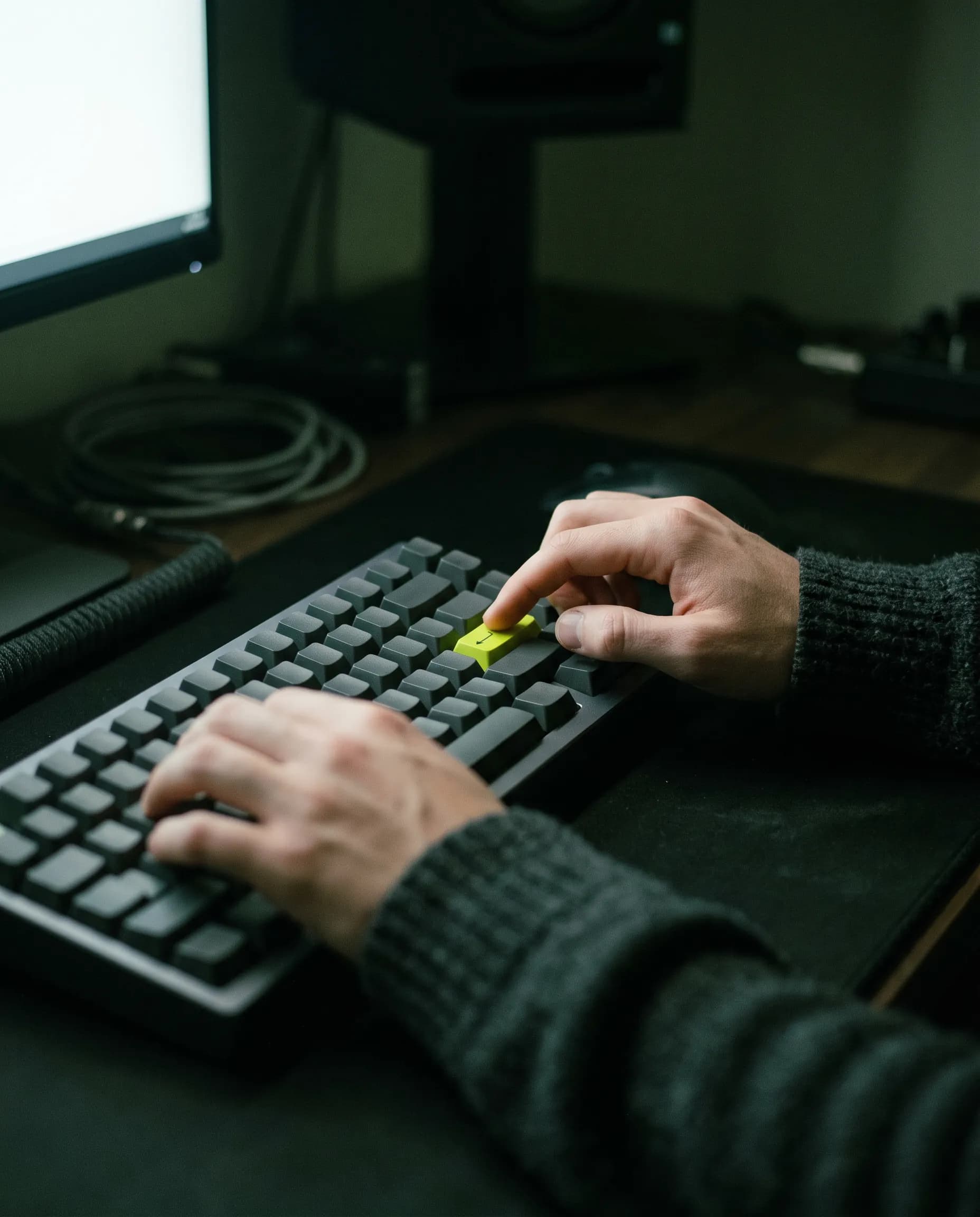 A developer’s hand about to press a green Enter key on a dark keyboard.